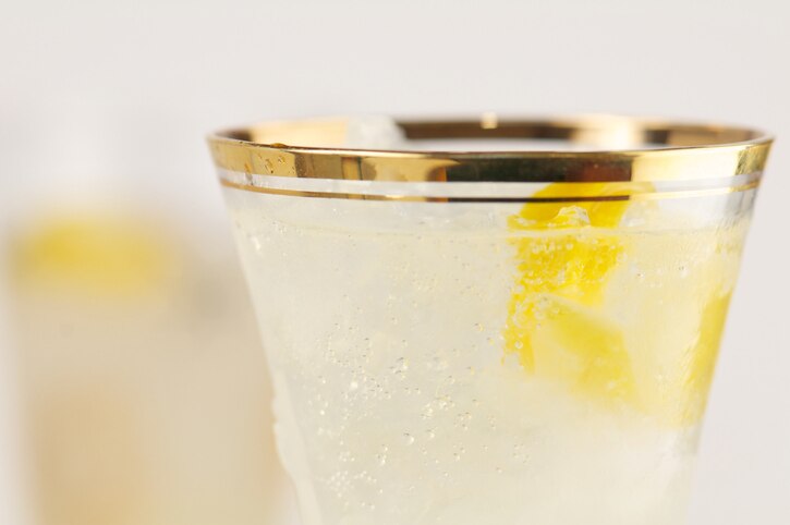 "Selective focus gold-rimmed glass filled with French 75 cocktail of champagne, gin and lemon."
