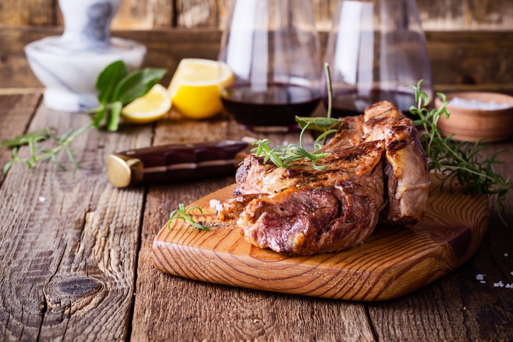 Barbecue bone ribeye steak on rustic cutting board ready to eat, delicious dinner with glass of wine